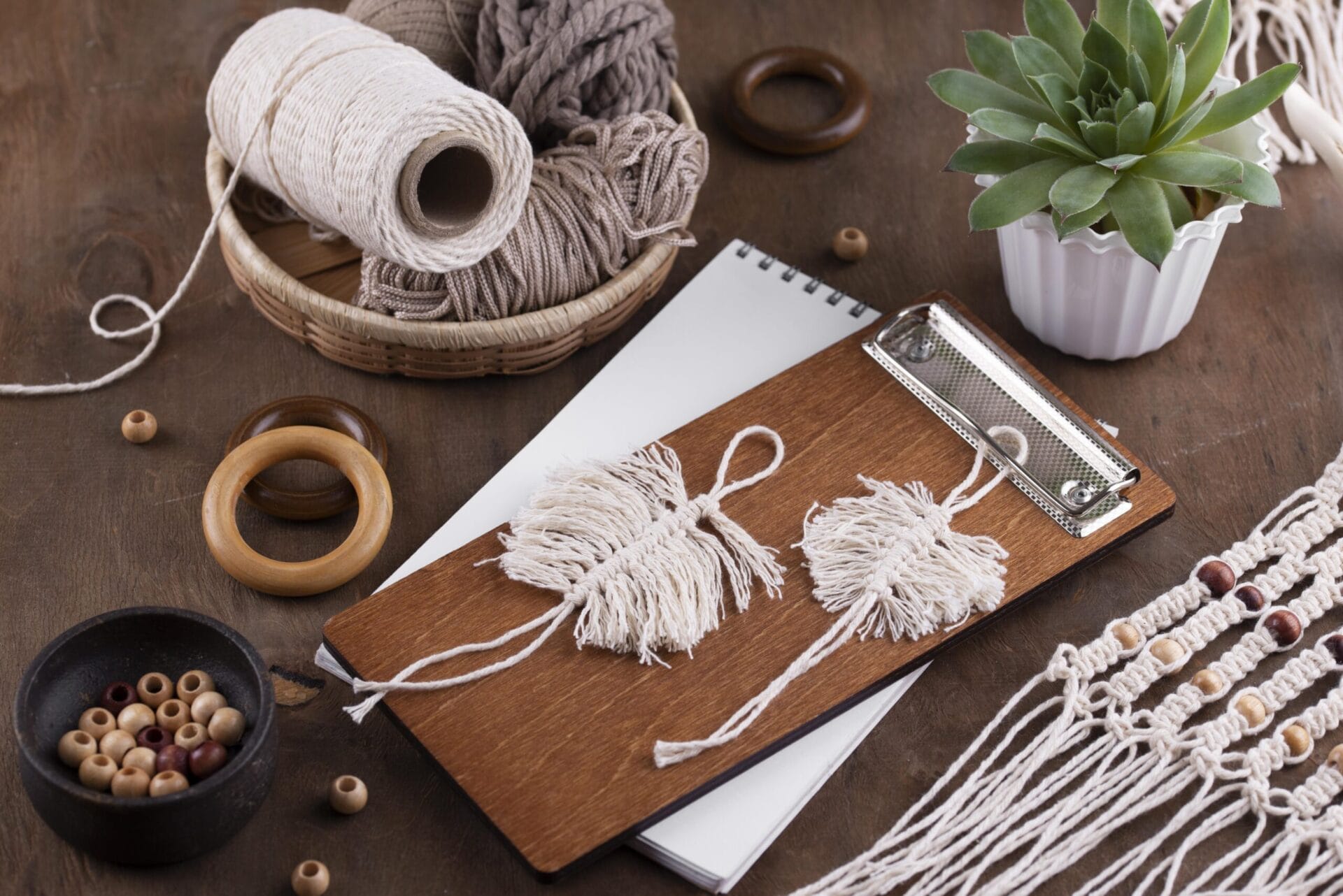 Feuilles décoratives en macramé faites main avec des perles et des anneaux en bois, disposées sur une table.